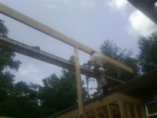 Carpenter setting a ridge beam over a new addition frame — Ice Dam Removal by Roofing Brothers in East Jewett