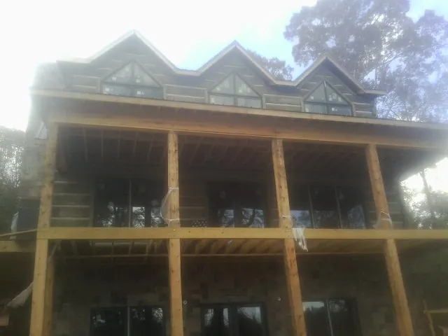 Dormers and porch framing on a large log home under construction — Roof Coating work by our crew in East Jewett