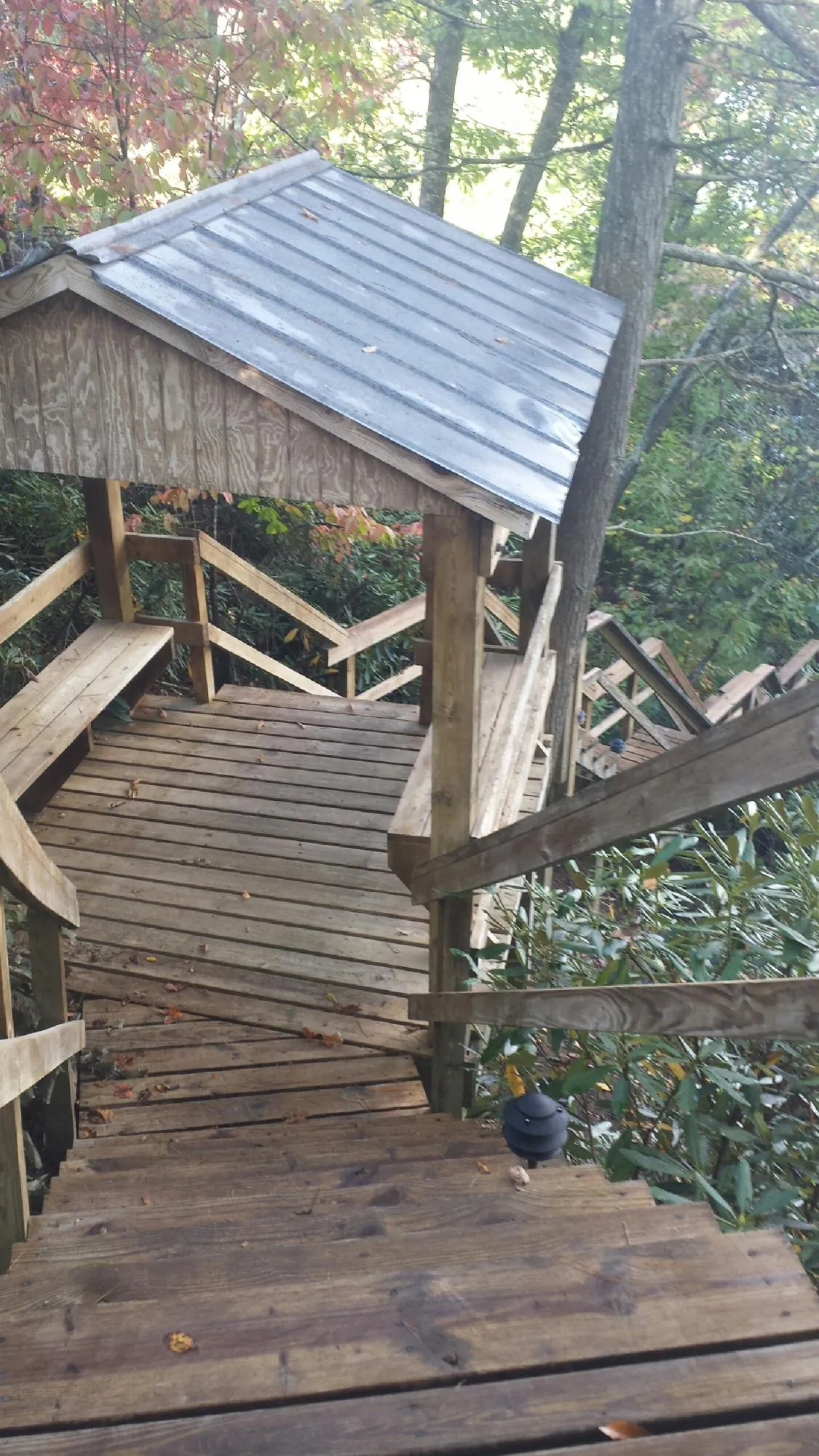 Metal roofed shelter over wooden steps on a wooded walkway — Skylight Repair & Installation work by our crew in East Jewett