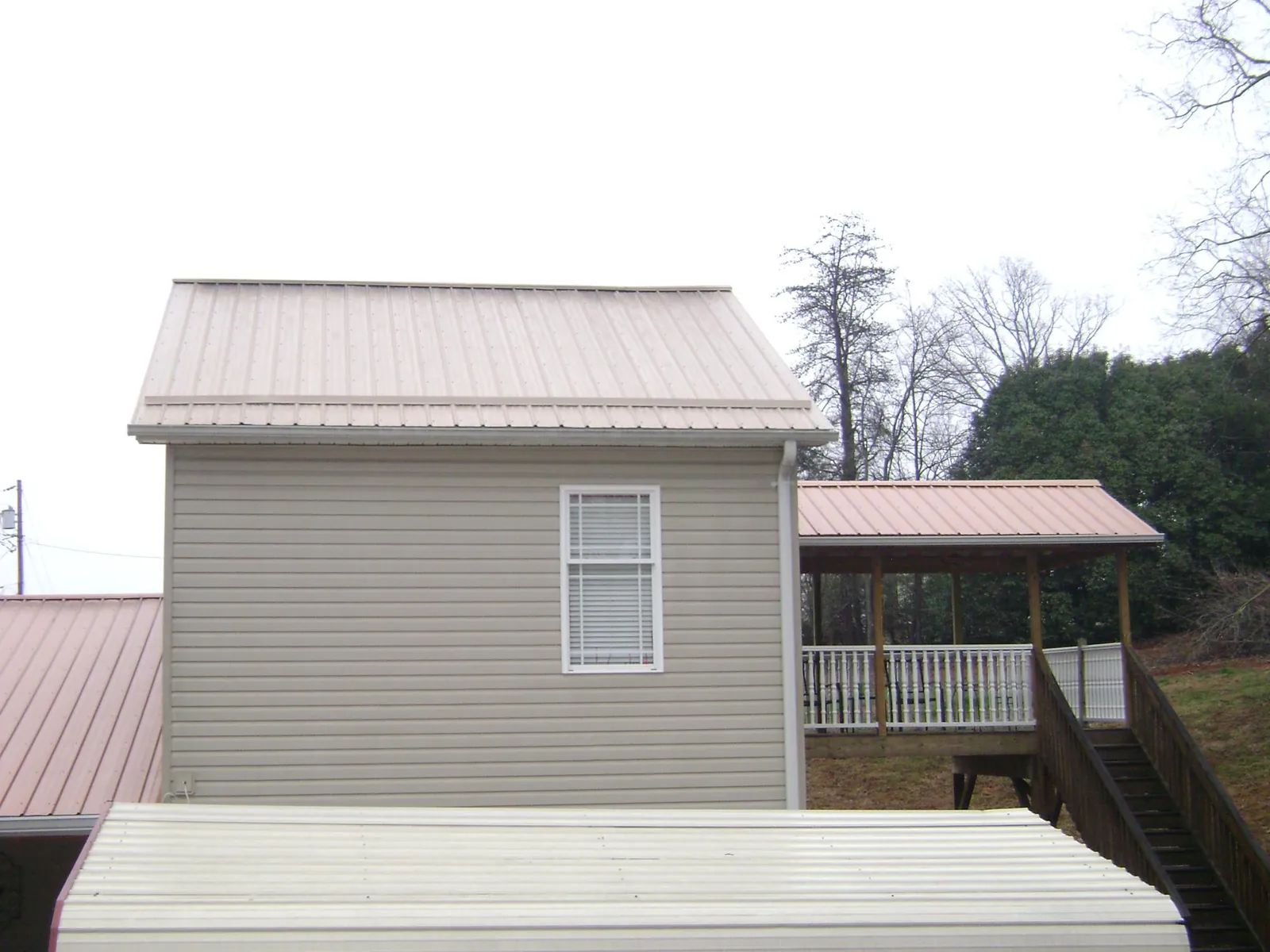 Tan metal roofs on a two story addition and attached porch, from a Roof Replacement job in East Jewett