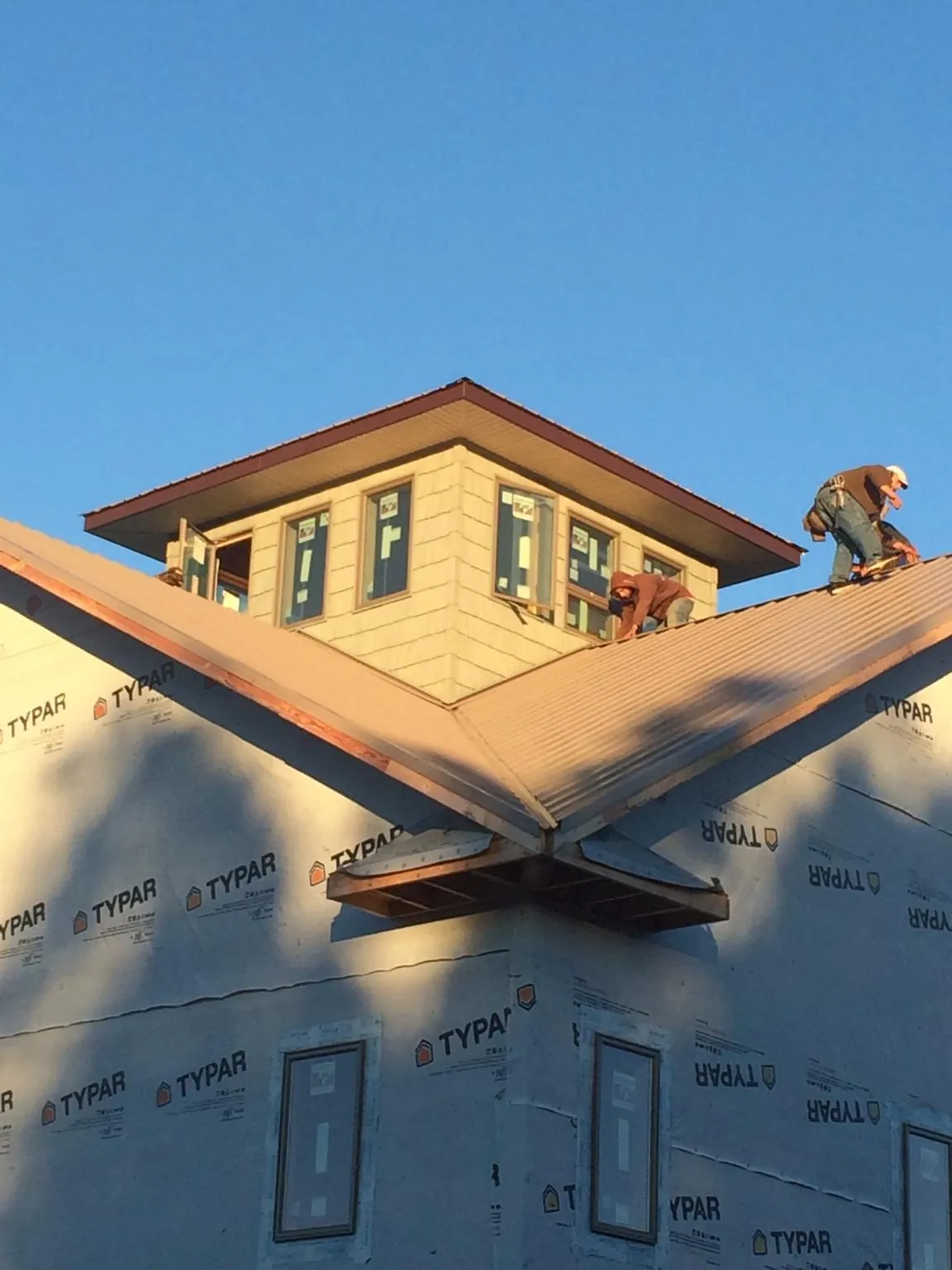 Roofers working around a rooftop cupola on a new metal roof at sunset — Roof Waterproofing in East Jewett by Roofing Brothers